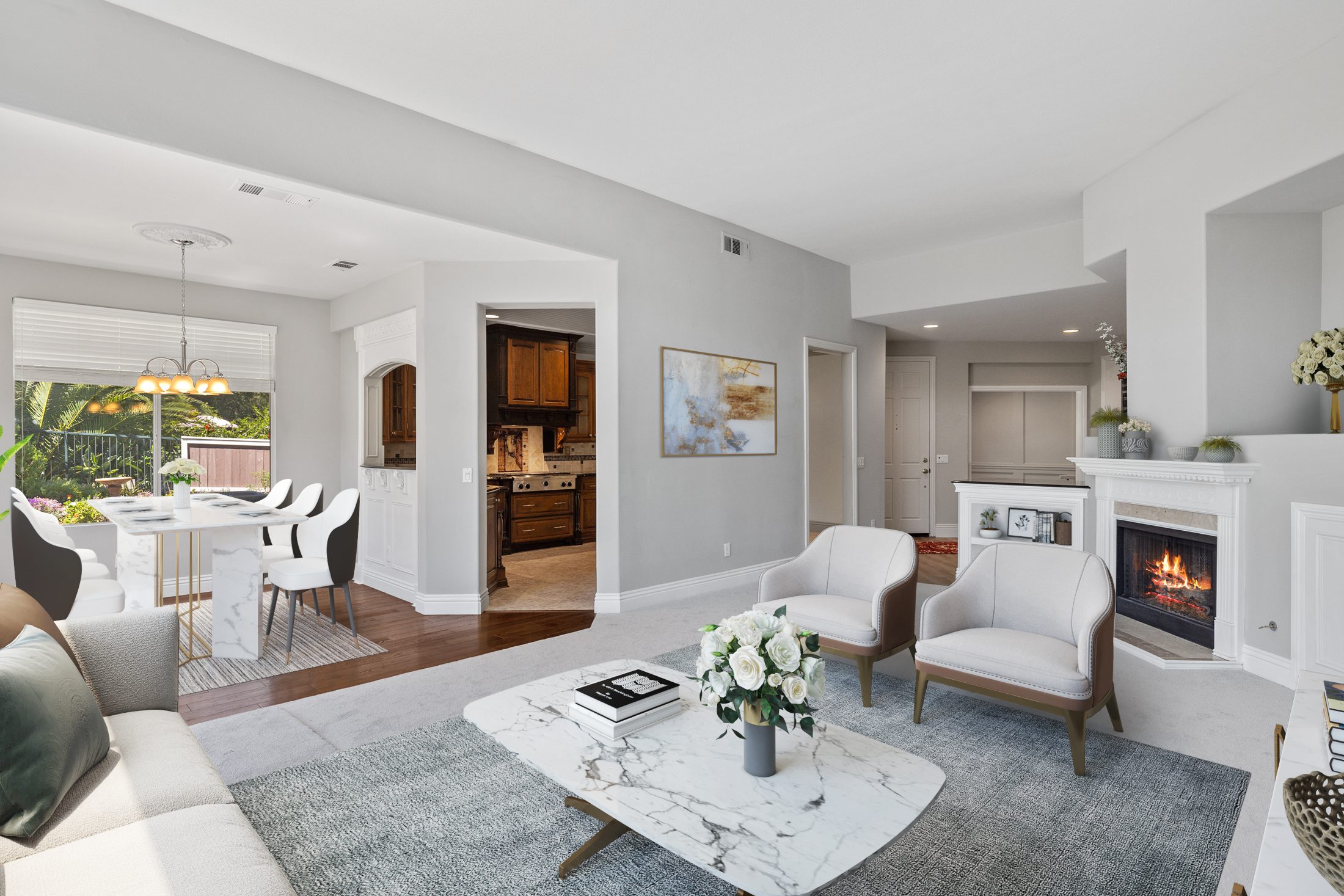 Modern open-concept living room with fireplace, marble coffee table, and kitchen visible through archway