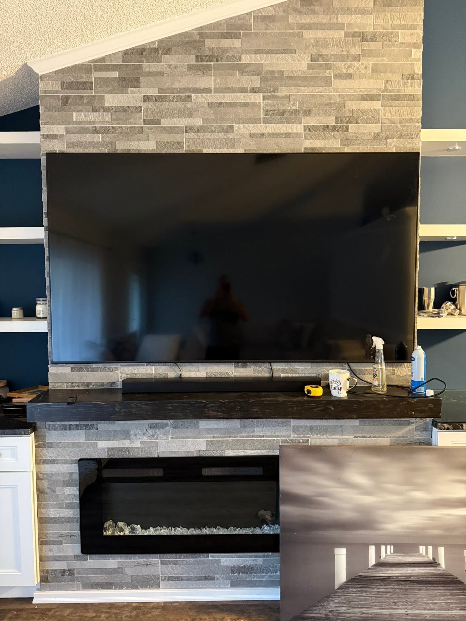Modern fireplace with stone tile surround, mounted TV, and electric insert with flame effect